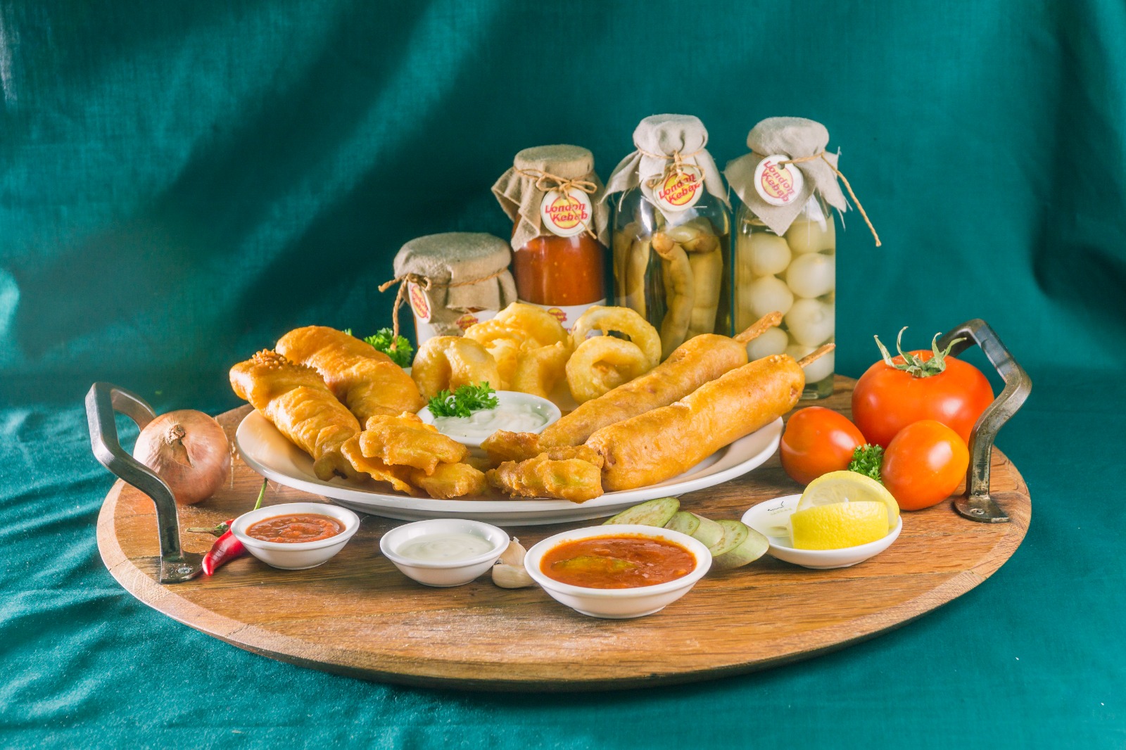 Battered fish, onion rings and house pickles on a wooden board